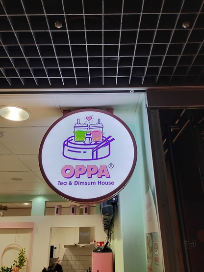 „OPPA Tea & Dimsum House“ im HBF-Untergeschoss, der/das mit rundem Schild Bubble Tea und ähnliches offeriert.