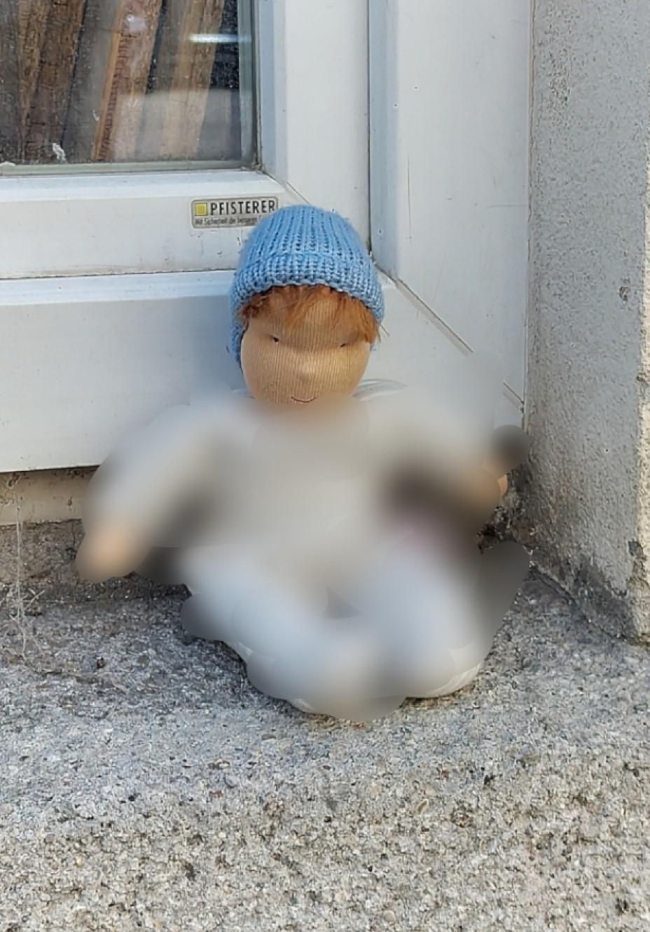 Stoffpuppe in einem Fenstersims sitzend
